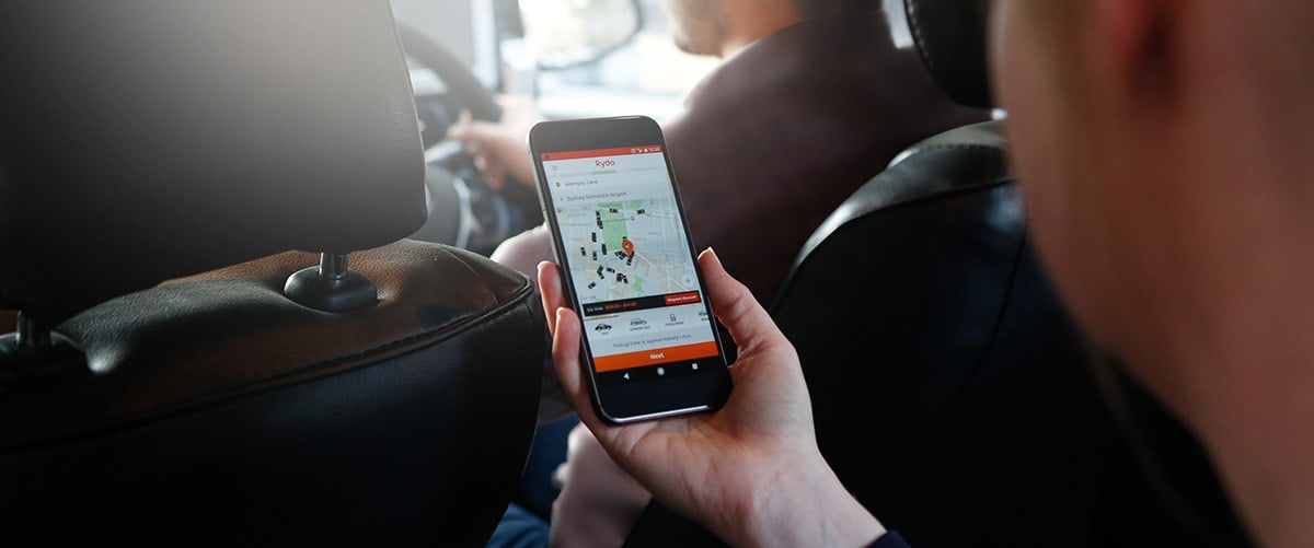 Passenger using the Rydo ride-booking app in a car